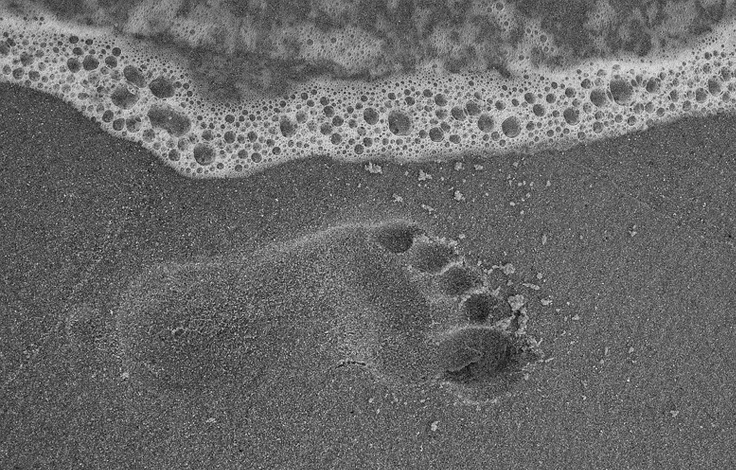 Fußabdruck im Sand, den die Brandung erreicht